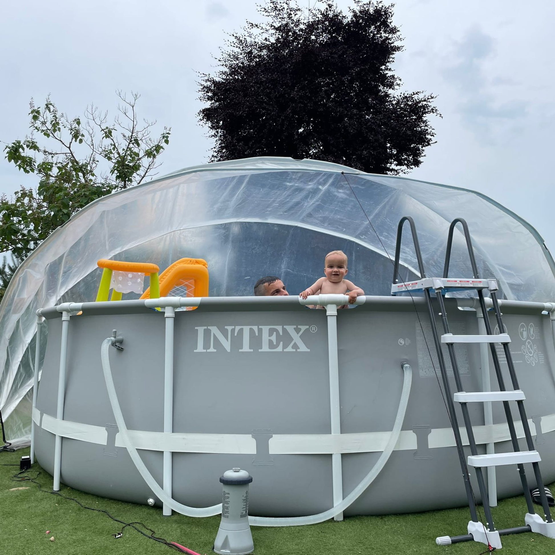 A large round pool dome covering an above-ground pool with a ladder, toys visible inside the pool.