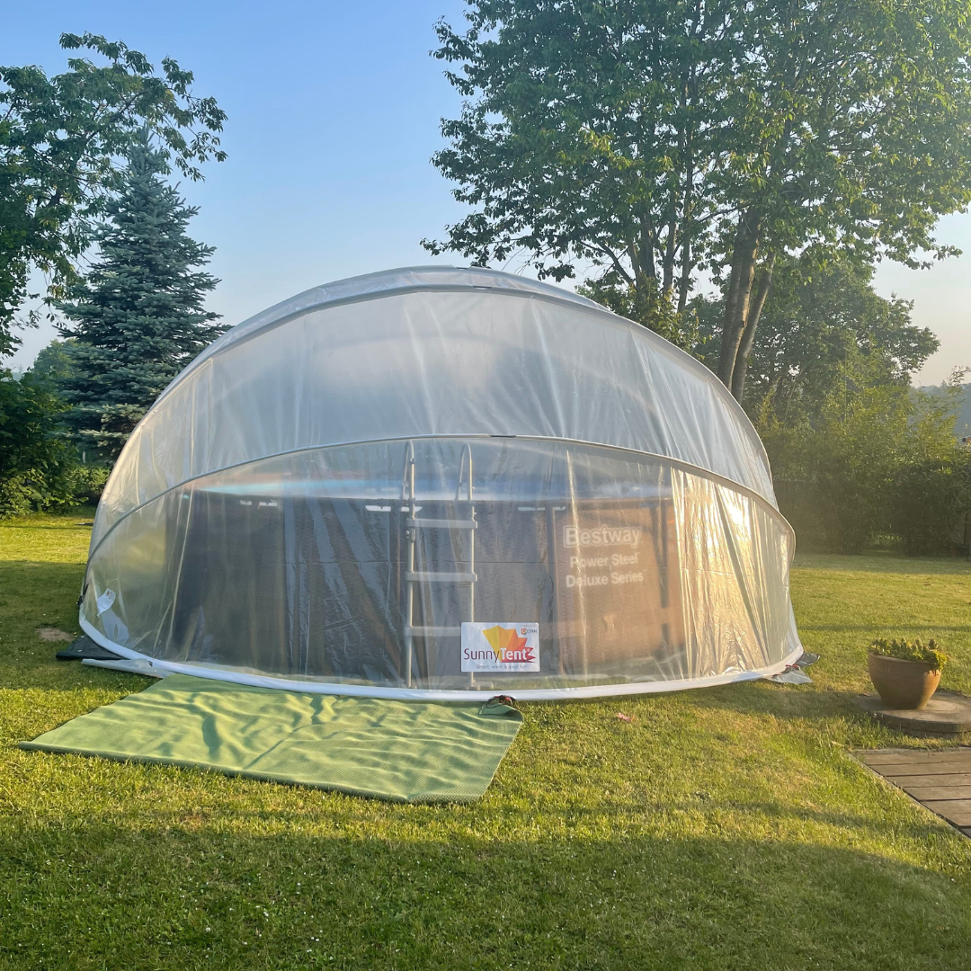 Clear dome tent on grass with trees in the background