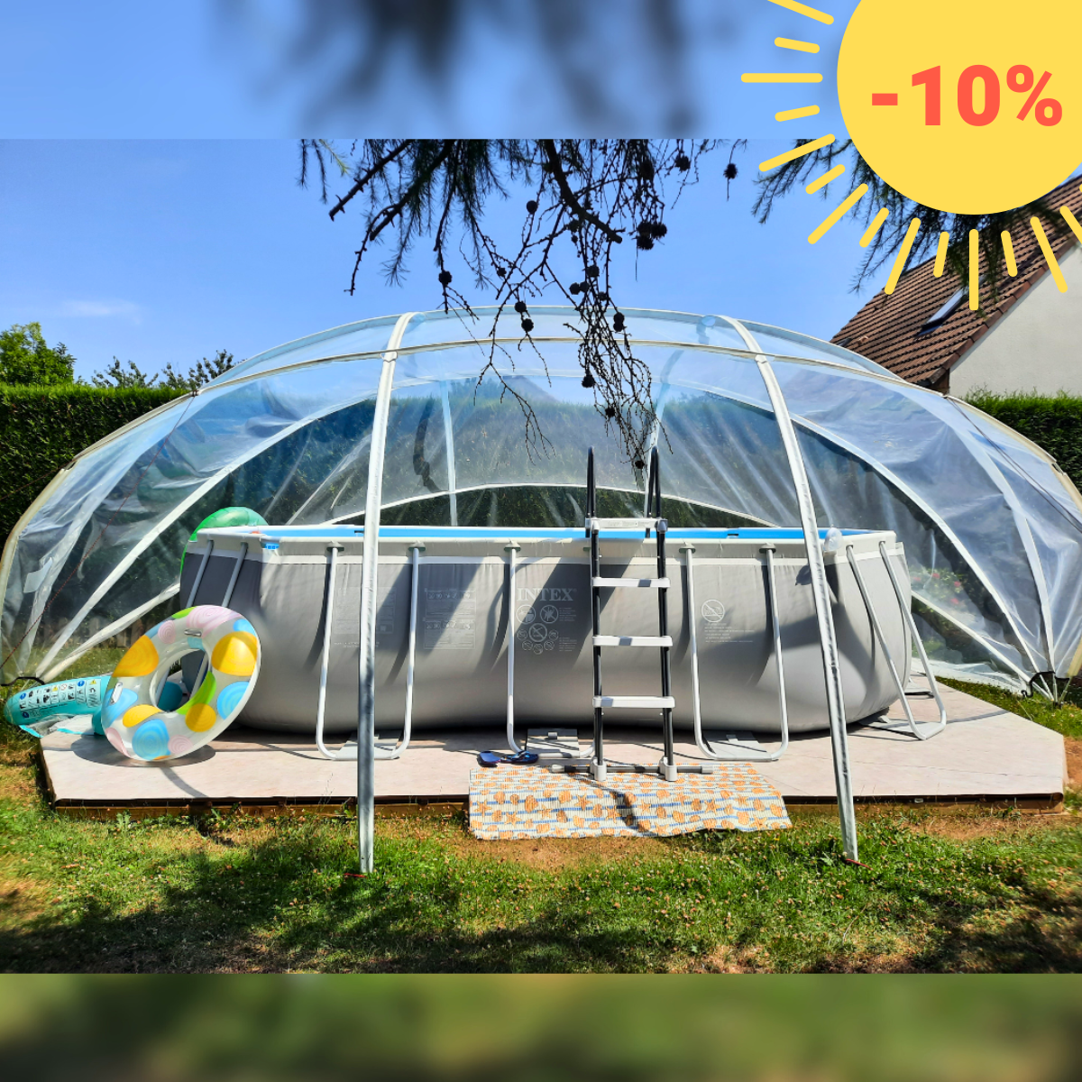 A clear, oval-shaped pool dome covering a pool area, set up on a grassy backyard with trees in the background.