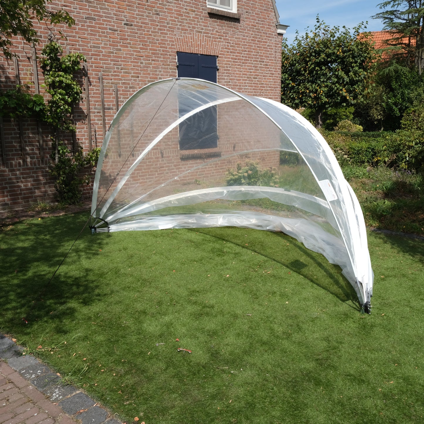 SunnyTent S - Jacuzzi dome on a grassy area with a brick building in the background